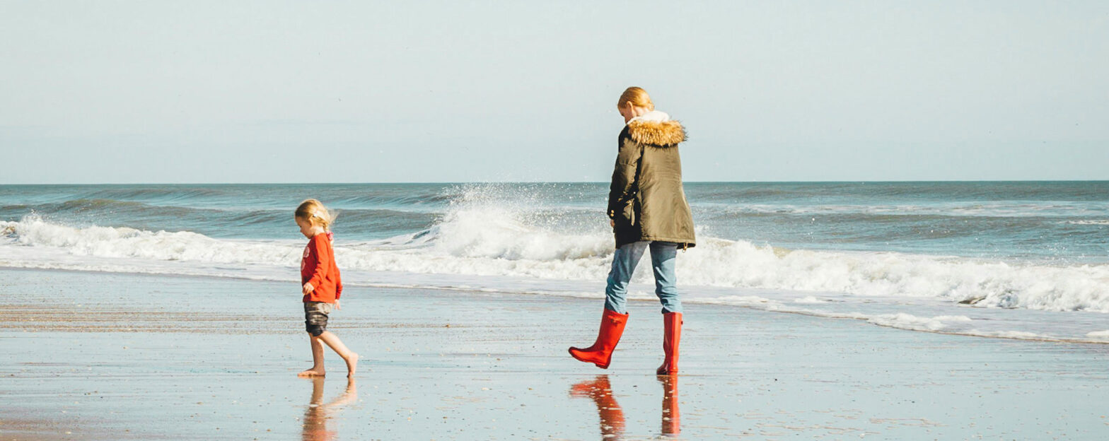 Person and child walking along a beach in Wales